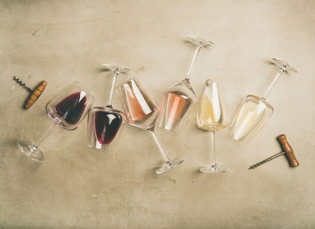 Wie glasses on their sides showing shades of wines from dark red to light white progressing through the glasses.