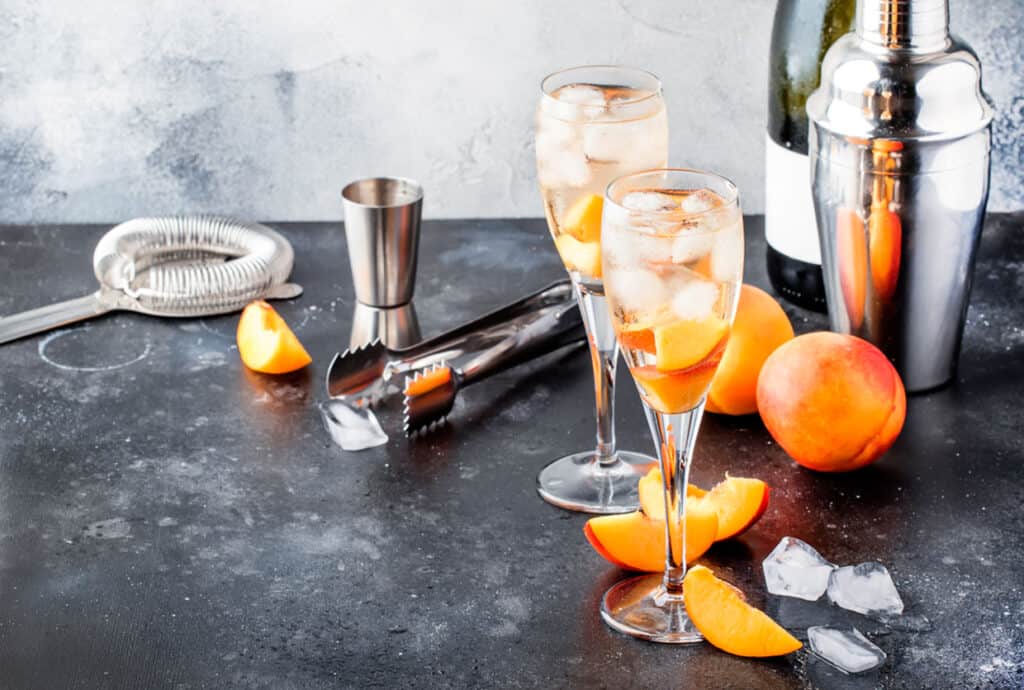 Cocktails on a counter with a cocktail shaker and other tools nearby.