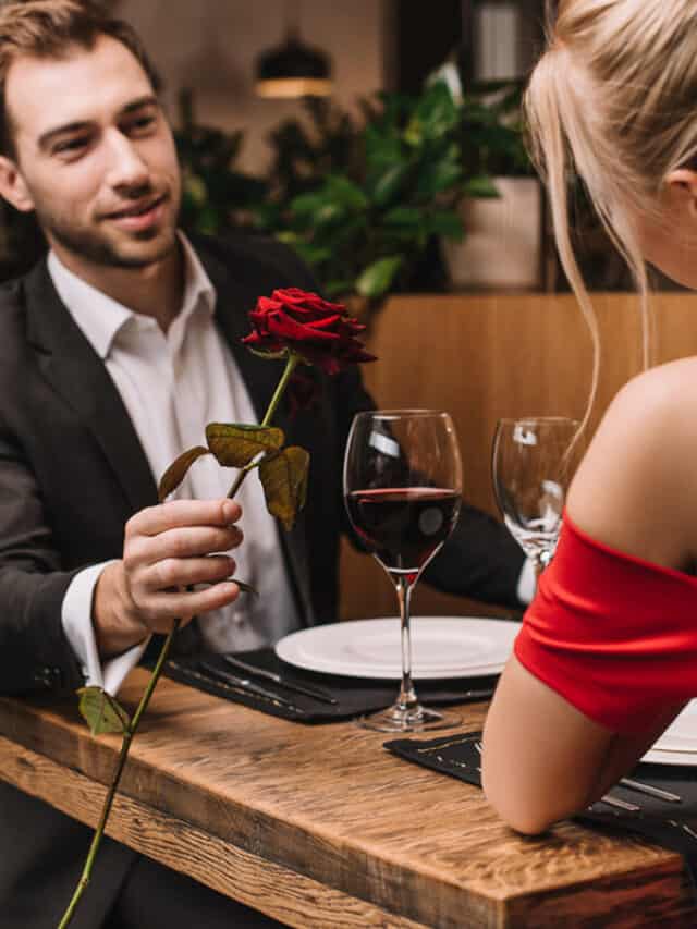 A man presenting a rose to a woman at a table.