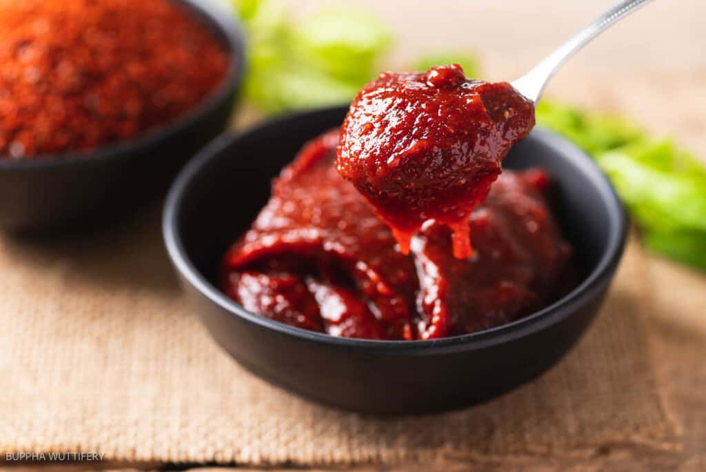 Gochujang in a bowl with a spoonful held above the bowl.