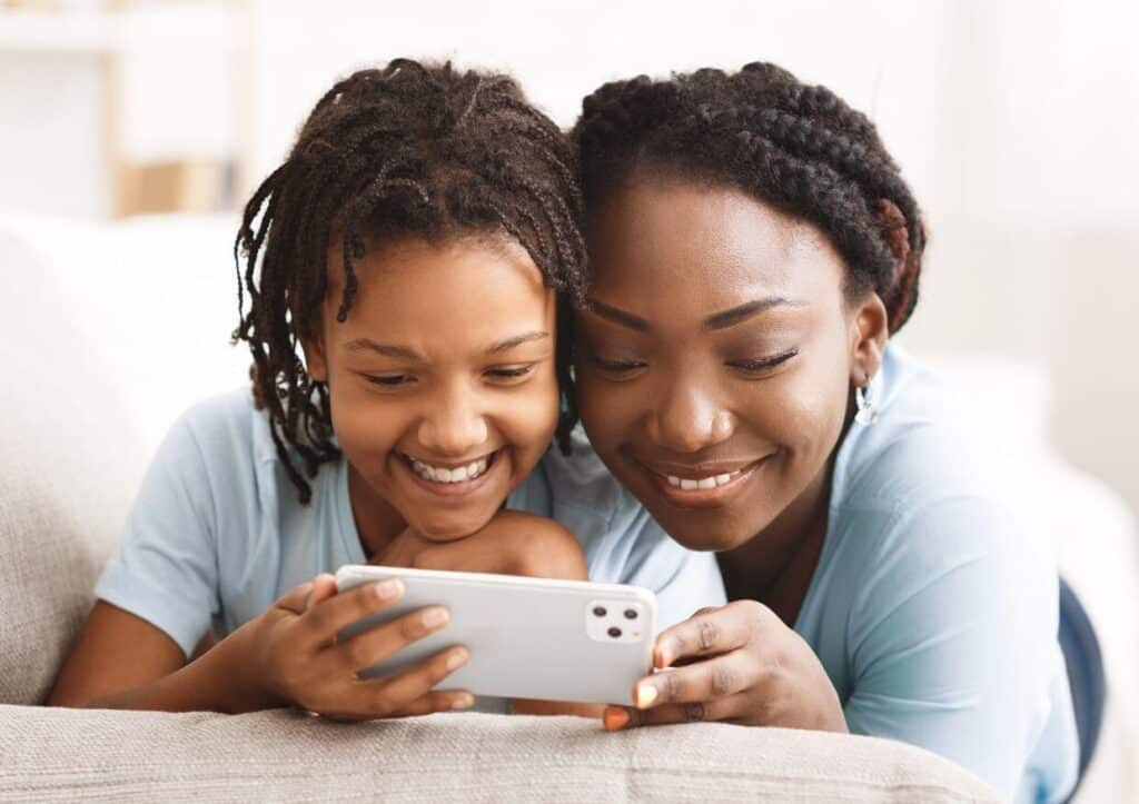 mother reviewing parental controls on iphone with daughter.