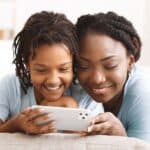 Mother reviewing parental controls on iphone with daughter.