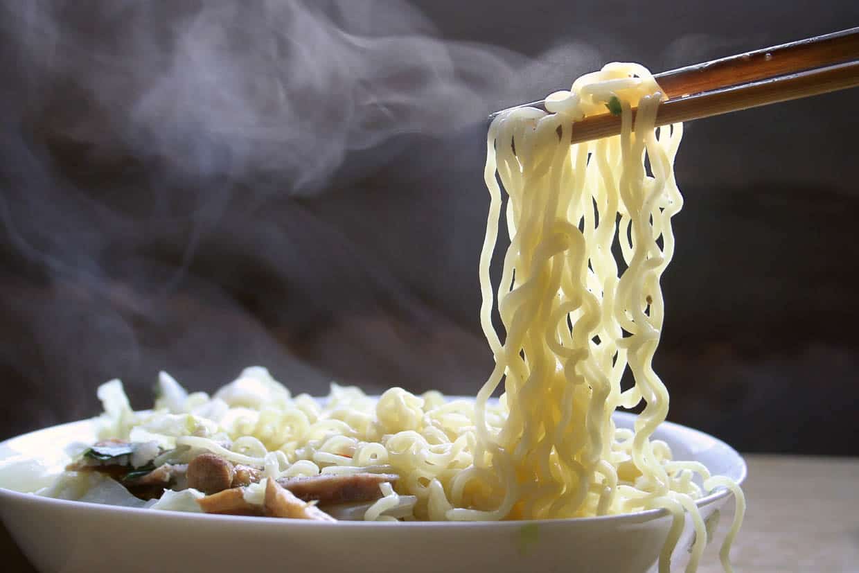 Ramen noodles being lifted from a steaming bowl of soup.