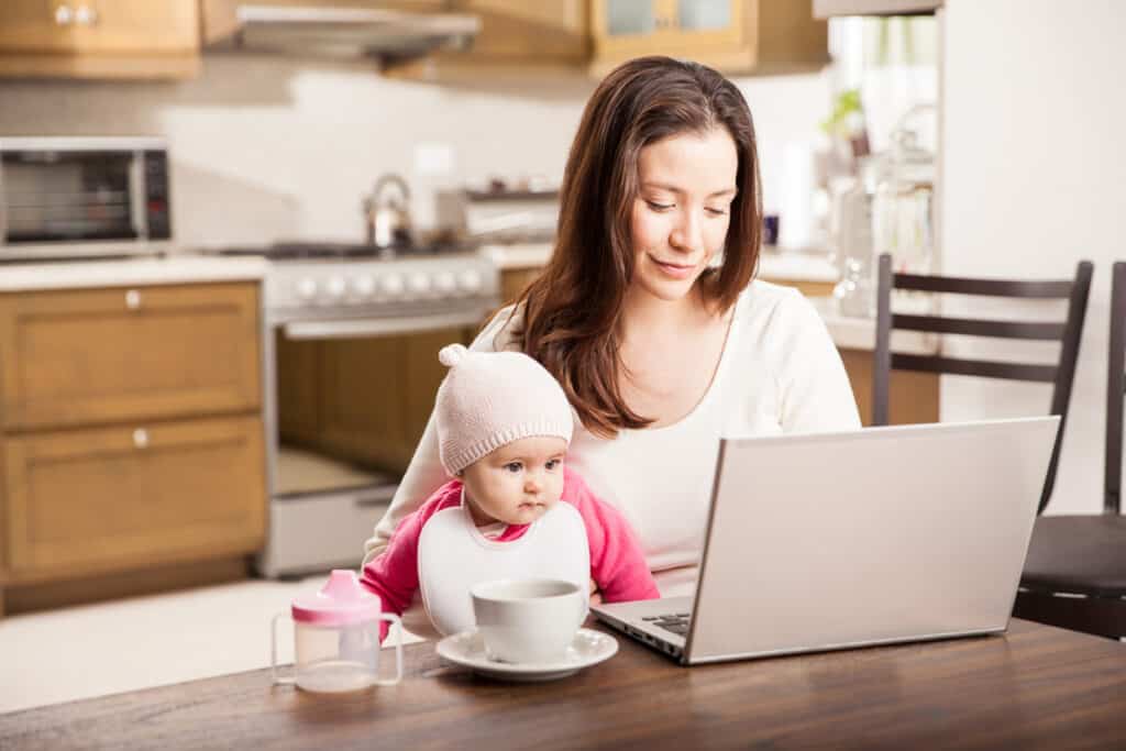 A mom and child in front of a laptop at the table.
