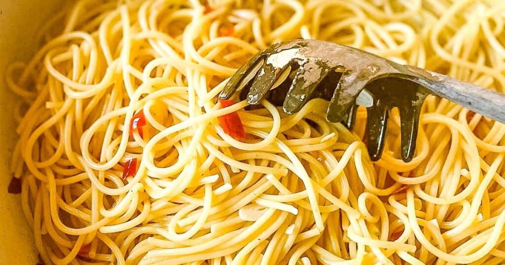 pasta aglio olio e peperoncino is mixed with a black pasta fork.