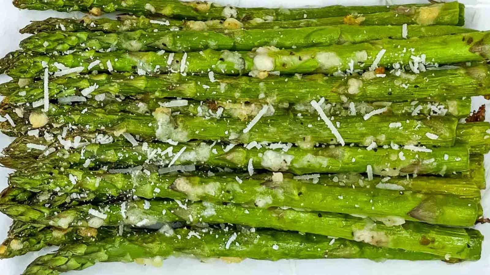 Air fried asparagus with garlic and parmesan on a white plate.