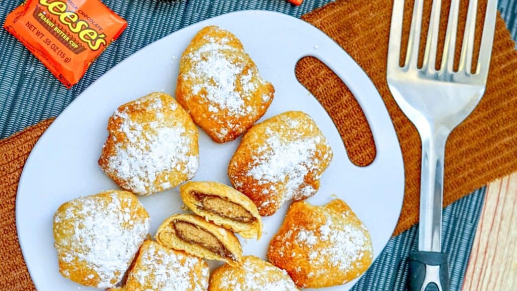 Air Fryer Reese’s dusted with powdered sugar with one cut open.