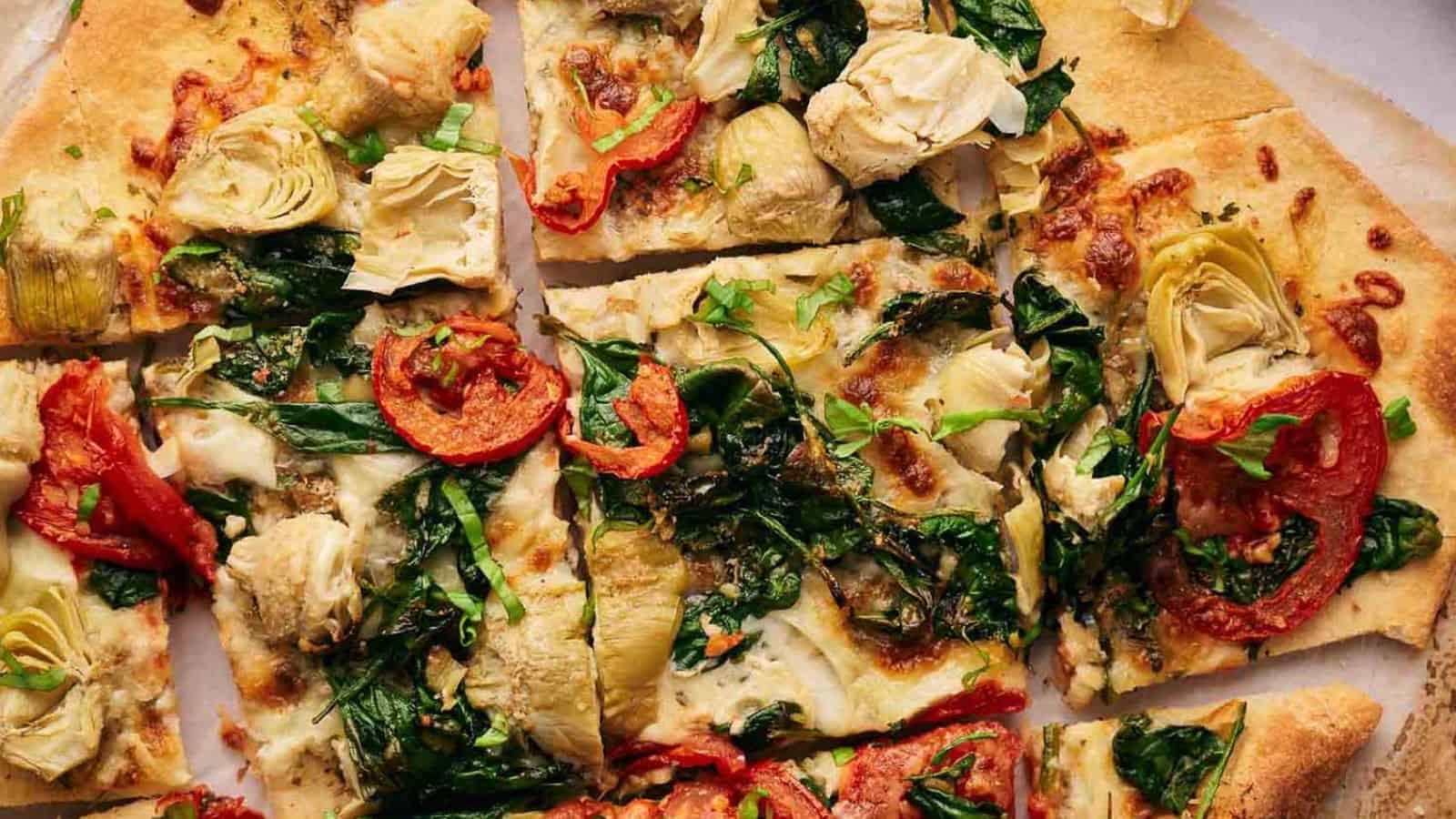 A pizza with artichokes, tomatoes and spinach.