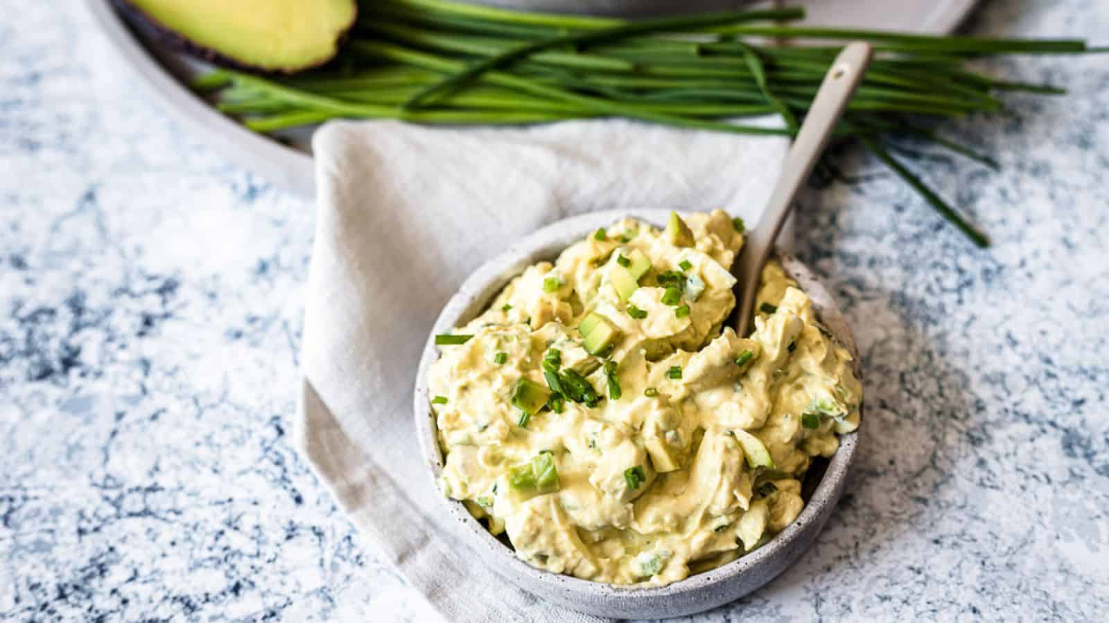 Avocado egg salad in small bowl with spoon.