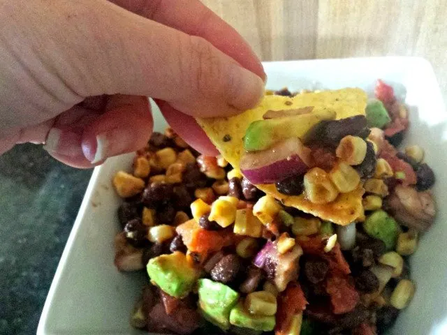 A corn tortilla chip with a scoop of black bean and corn salsa.