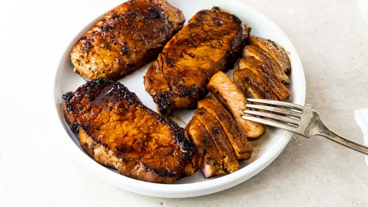 Pork Chops on the Blackstone Griddle on a whtie plate with a fork.