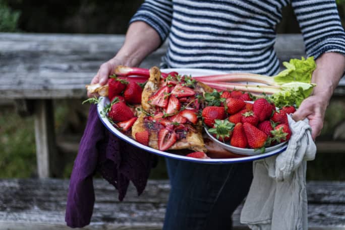 Roasted chicken on a platter with strawberries and rhubarb.
