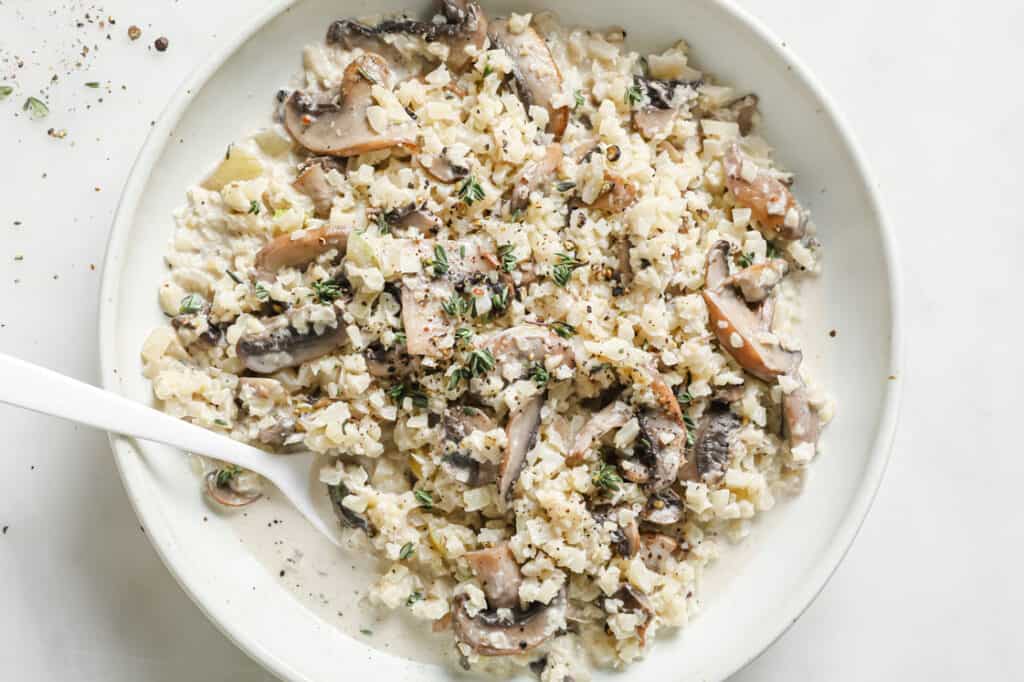 A dish of cauliflower risotto with mushrooms with a fork.