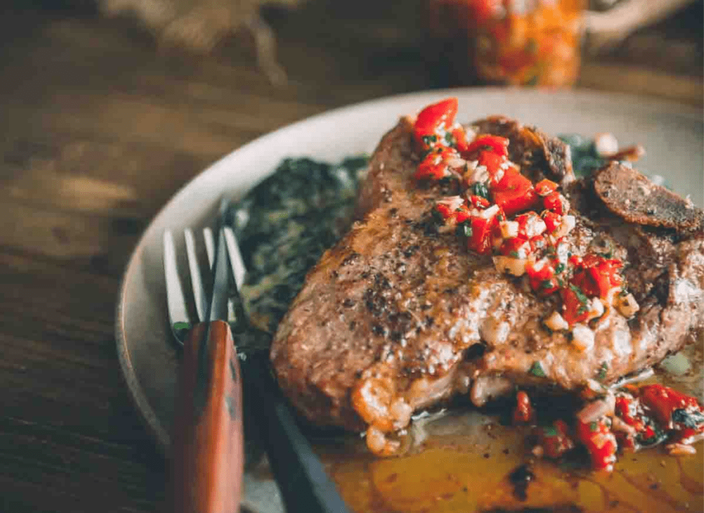 Red chimichurri spooned over grilled meat.