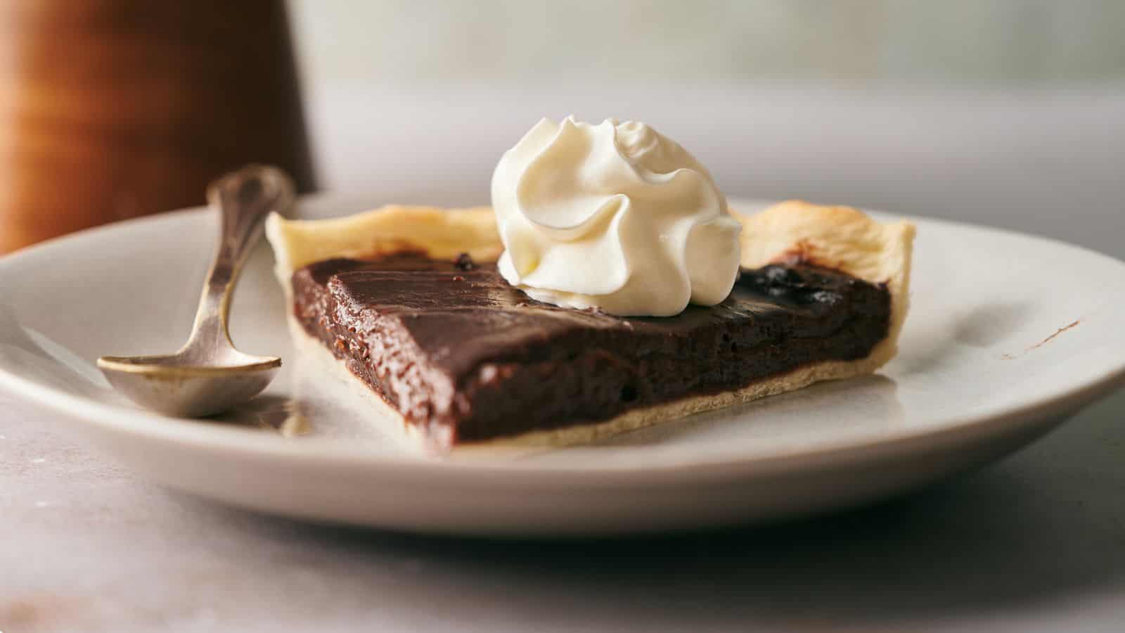 A slice of chocolate pie with a swirl of whipped cream.