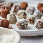 Chocolate truffles on a plate with a chocolatey spoon resting on the plate.