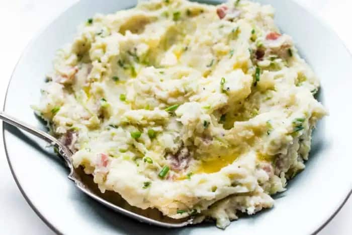Colcannon with bacon in a white serving bowl.