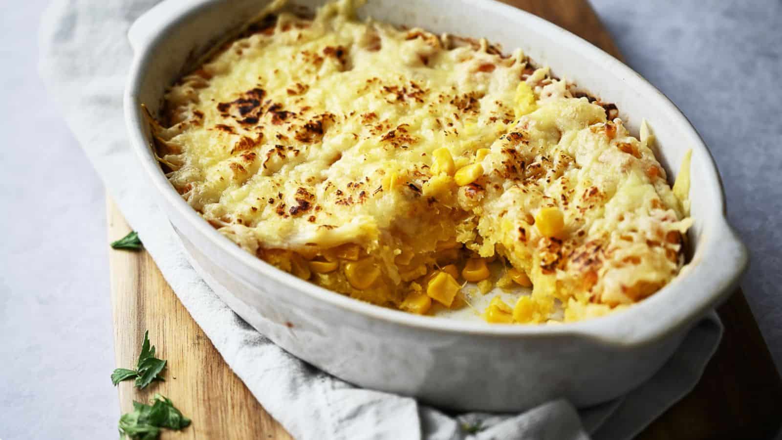 Corn casserole in a casserole dish with a portion removed.