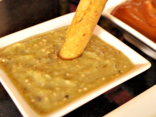 Creamy tomatillo salsa with a taquito dipped in it.