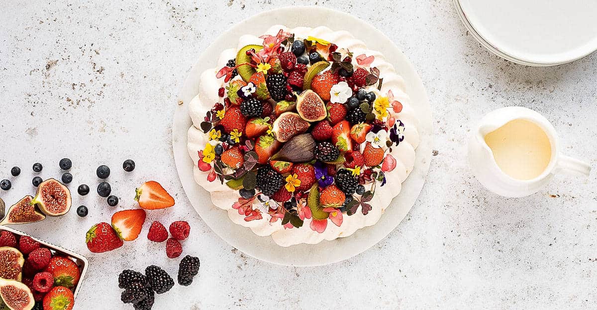 A pavlova topped with berries and figs.