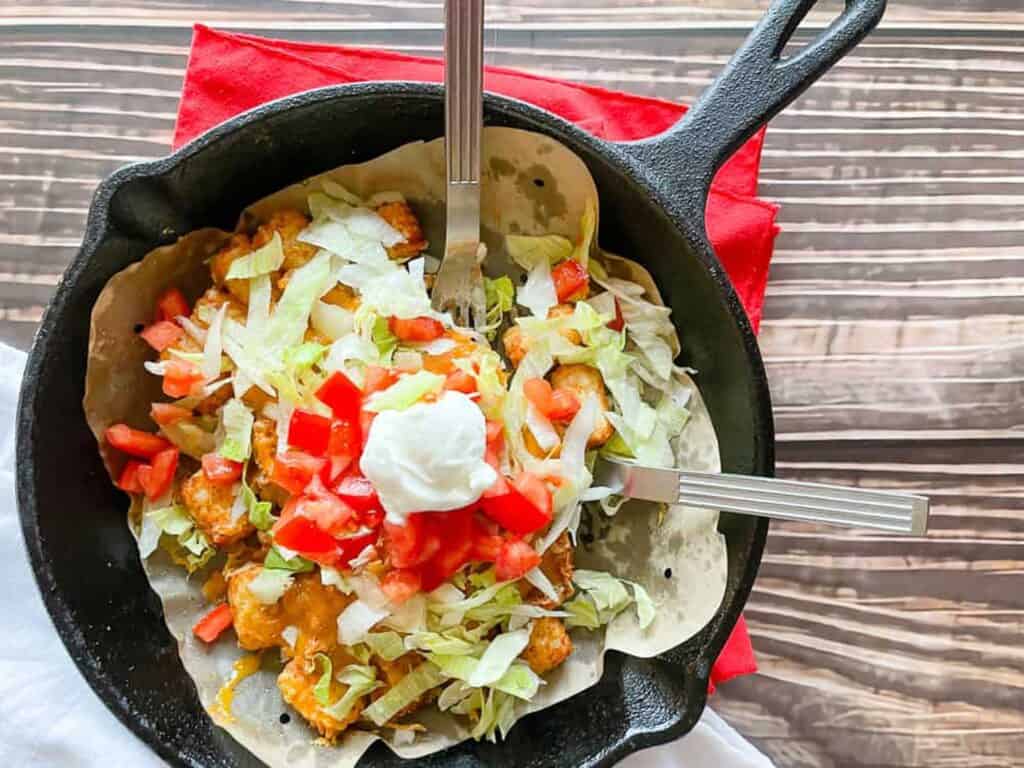 Air Fryer Totchos in a skillet on a red linen. 