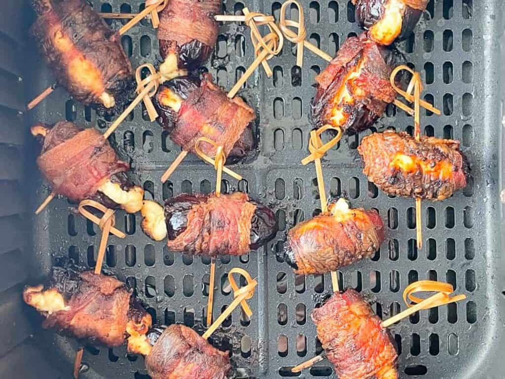 Bacon Wrapped Dates in an air fryer basket. 