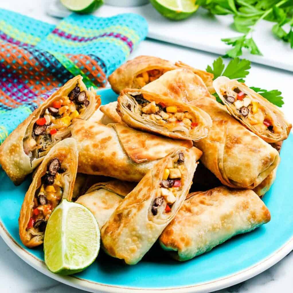Southwest egg rolls on a blue plate with a slice of lime. 