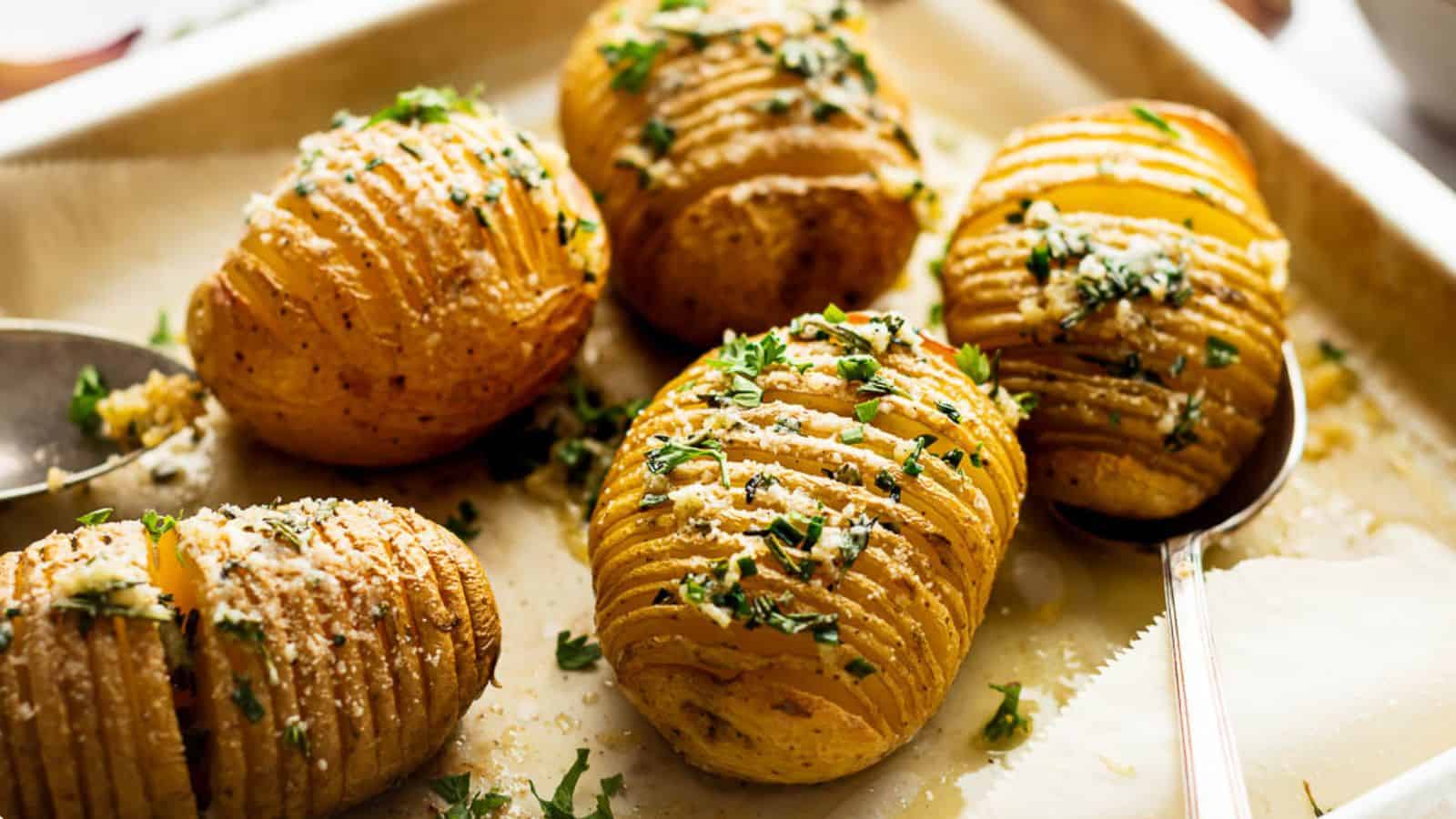 Roasted hasselback potatoes on a baking sheet with parmesan.
