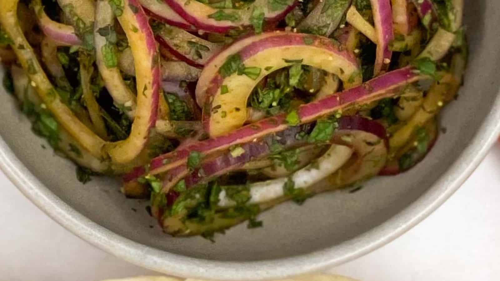 A bowl of red onion and cilantro salad on a table.