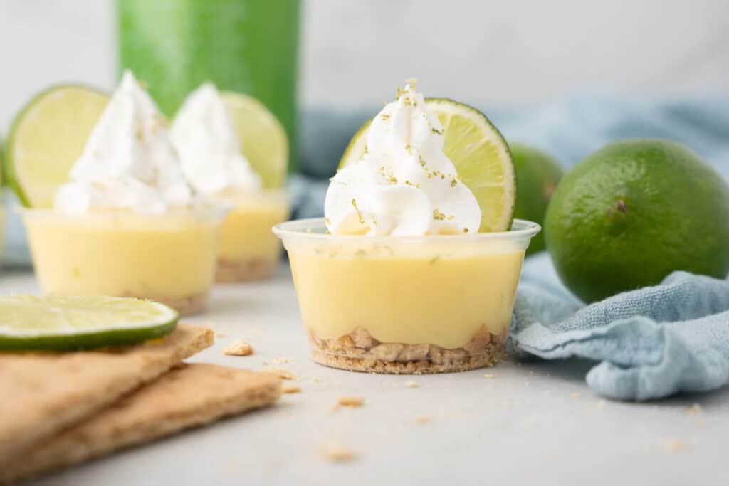 A key lime pie jello pudding shooter with whipped cream on top.