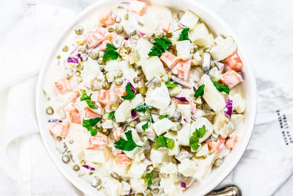 A white bowl of potato salad with mayonnaise.