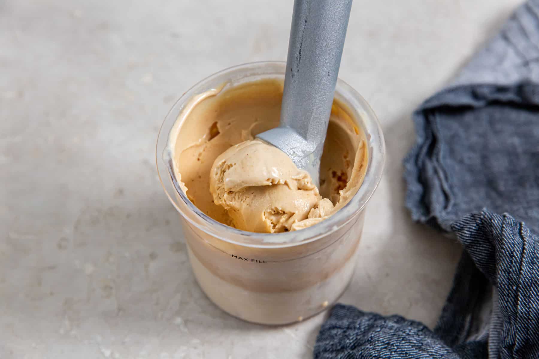 Ninja Creami Peanut Butter Ice Cream in a glass jar with an ice cream scooper.