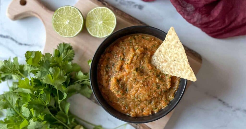 pineapple habanero salsa in a black bowl on a wooden cutting board.