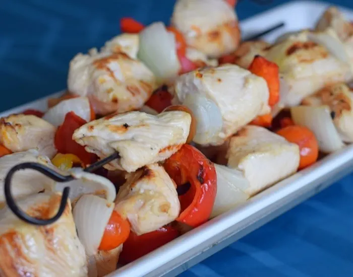 Lemon Marinated Chicken Kebabs on a platter with blue background.