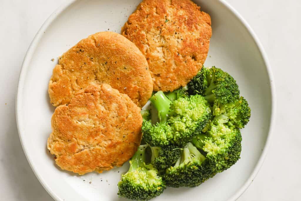 Canned chicken patties on a plate with broccoli.