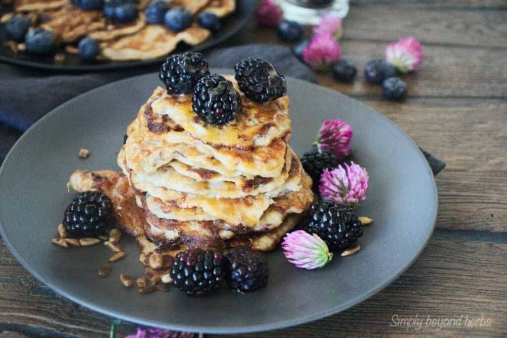 A stack of pancakes topped with berries and flowers.