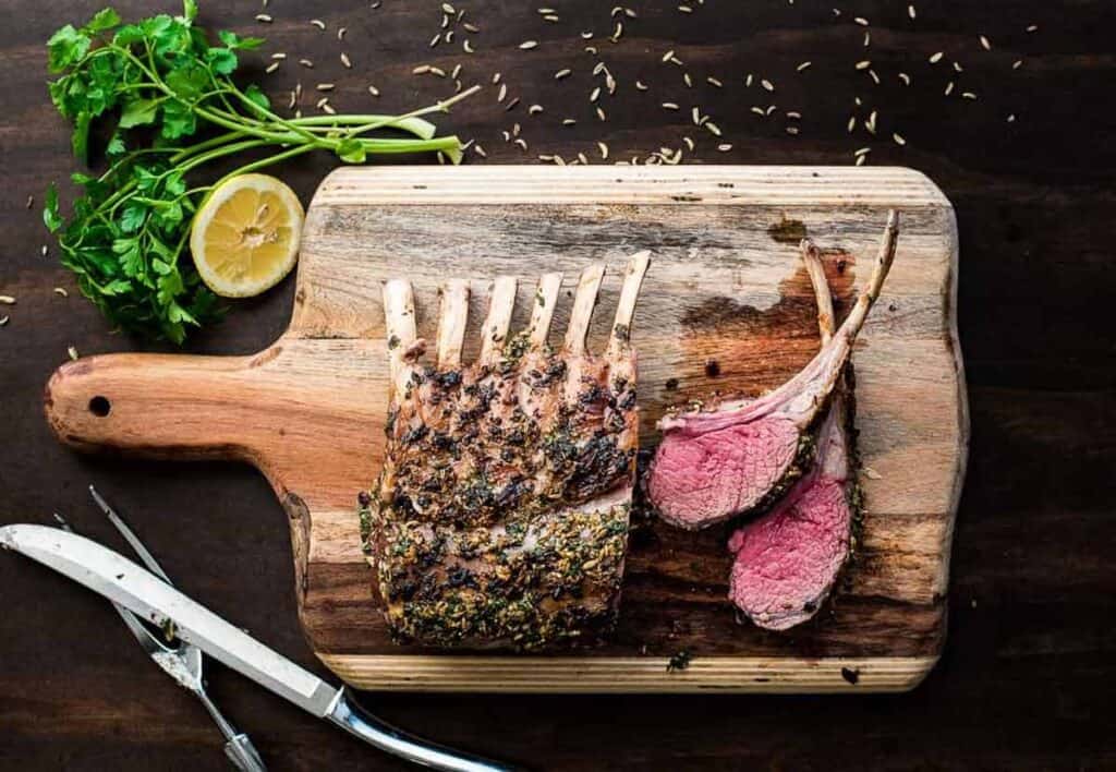 Roasted rack of lamb on a cutting board.