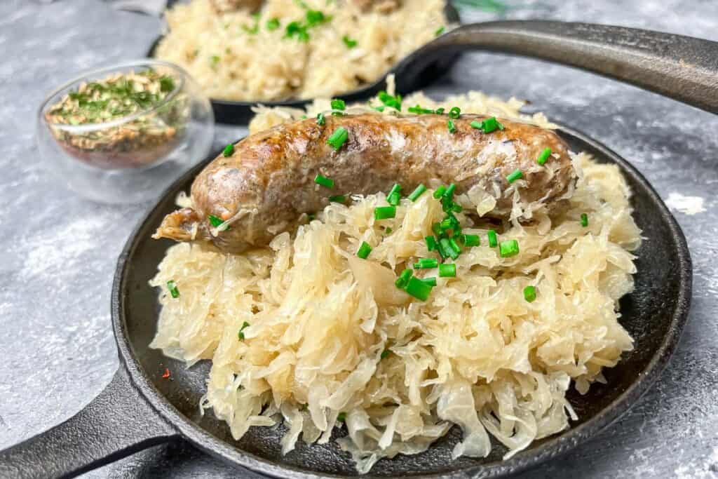Baked sausage and sauerkraut in a black pan.