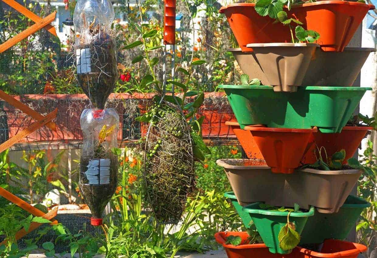 Vertical gardening using pop bottles and planters on a balcony.