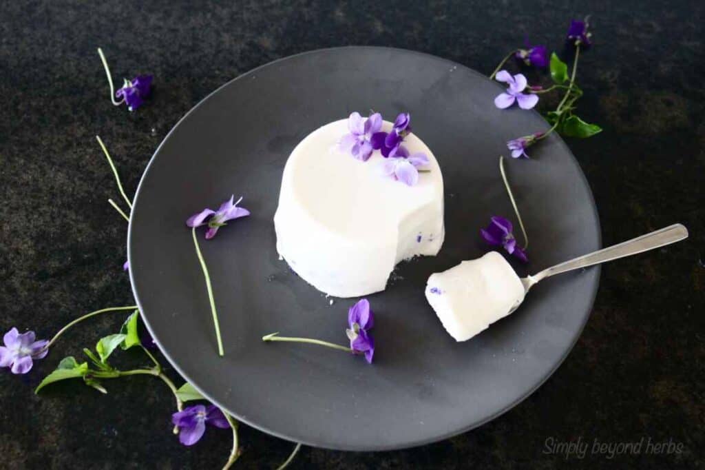 A white dessert topped with purple edible flowers.