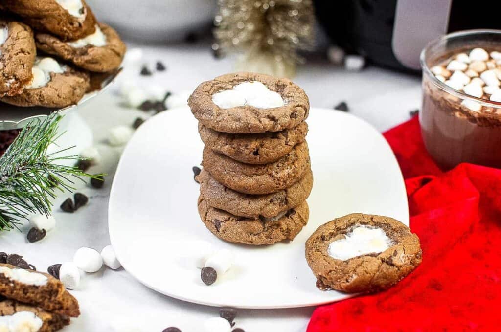 Air Fryer Hot Cocoa Cookies topped with marshmallow and stacked on a plate.