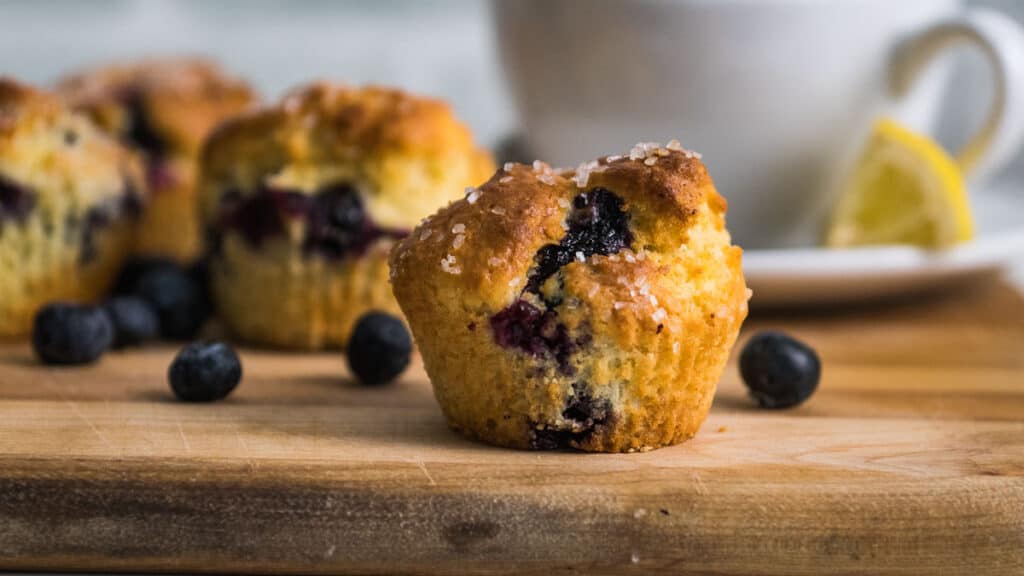 Air Fryer Blueberry Muffins on a cutting board with tea in the background.