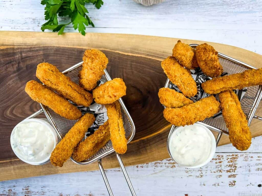 Air fryer chicken fingers in baskets with dipping sauce.
