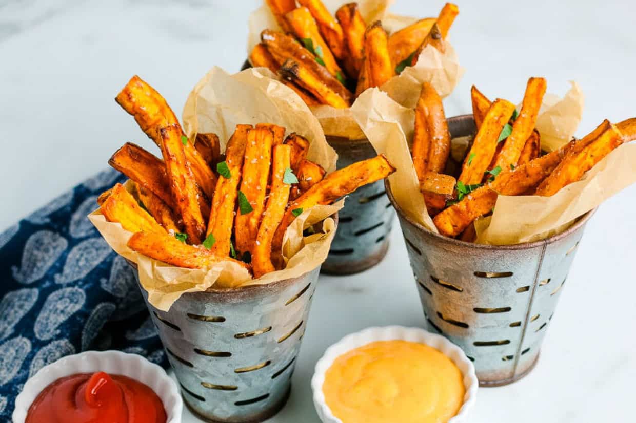 Air fryer sweet potato fries in three metal fry containers with dipping sauce.