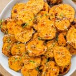 Air fryer sweet potato rounds with a parmesan herb crust garnished with thyme sprigs on a plate.