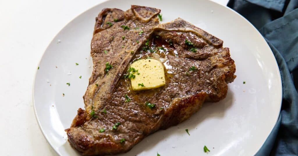 air fried t bone steak on a white plate with butter.