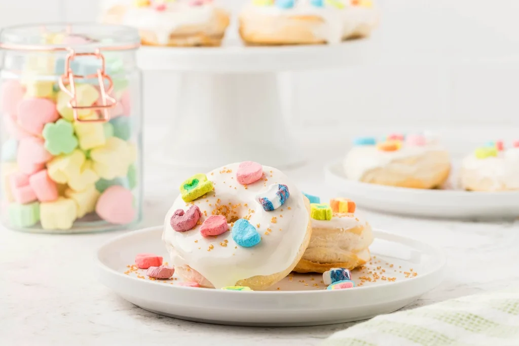 air fryer donuts topped with glaze and lucky charms cereal.