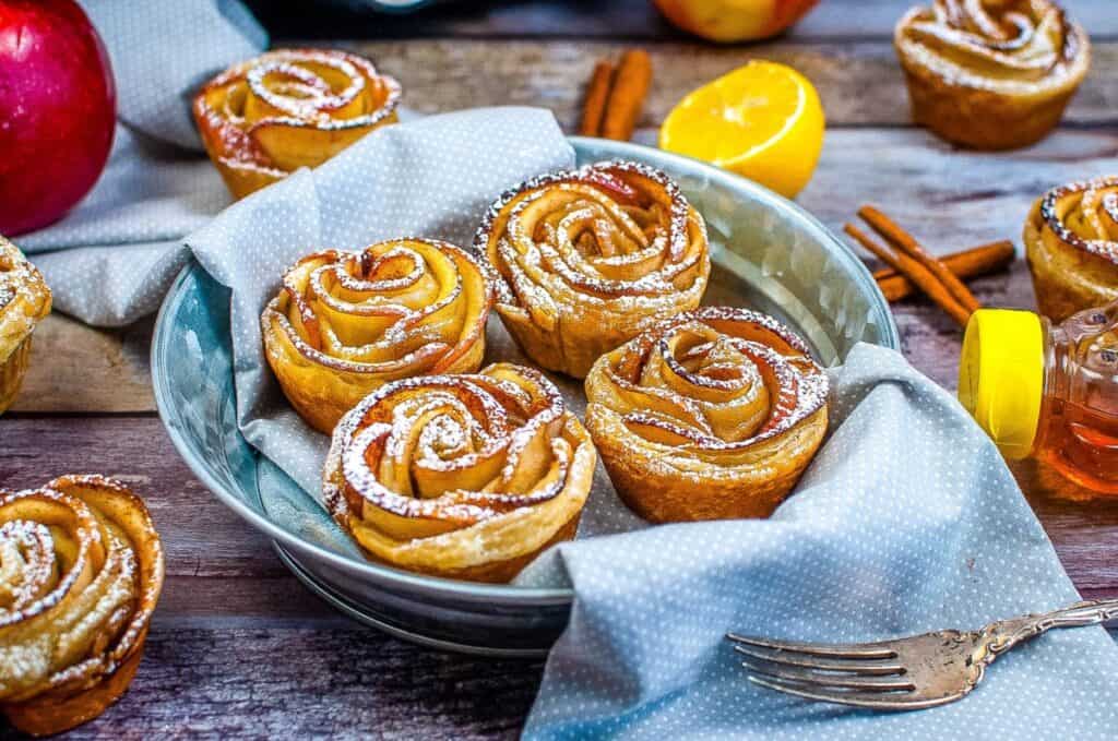 Air Fryer Apple Roses dusted with powdered sugar on a plate.