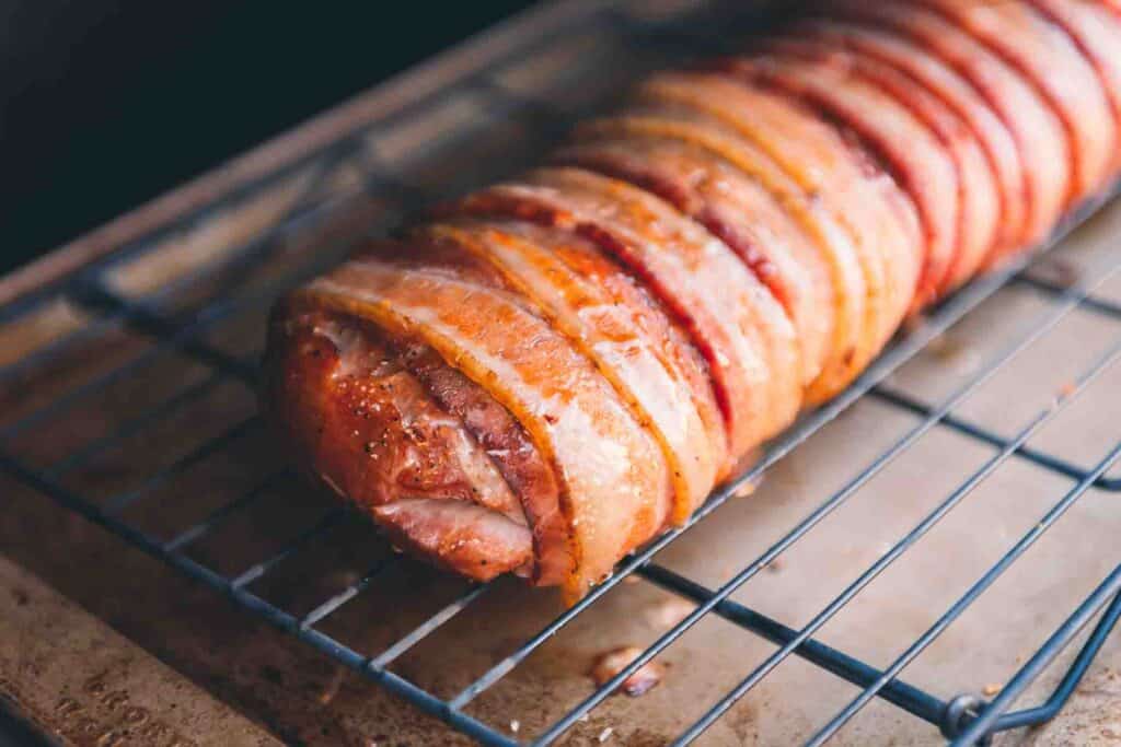 A bacon wrapped smoked pork loin on the grill.