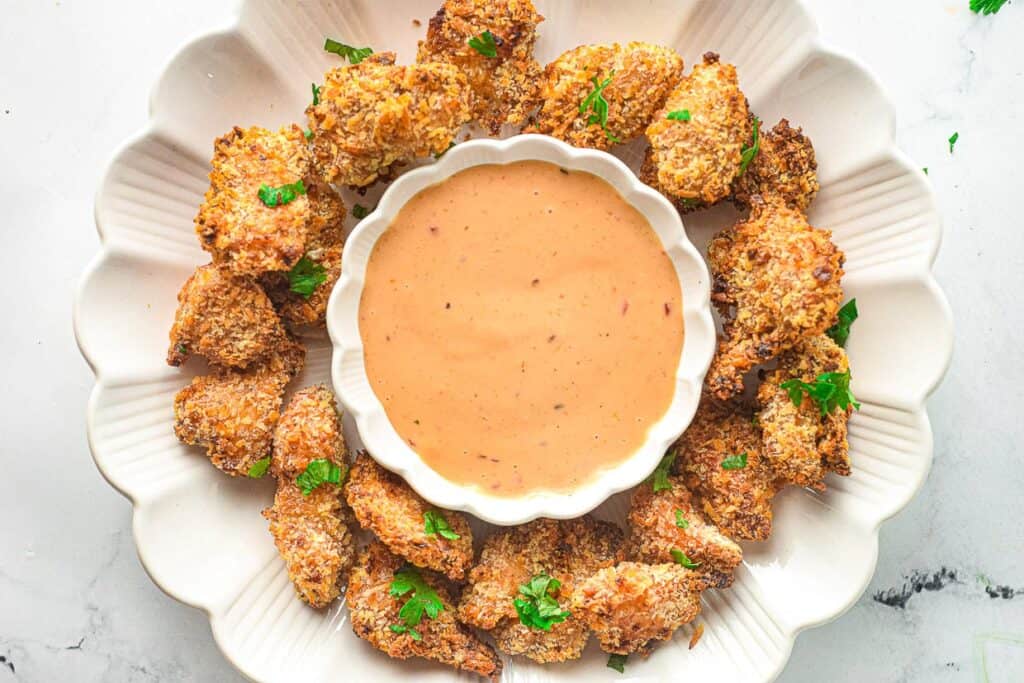 Bang bang chicken on a serving platter surrounding a bowl of bang bang sauce.